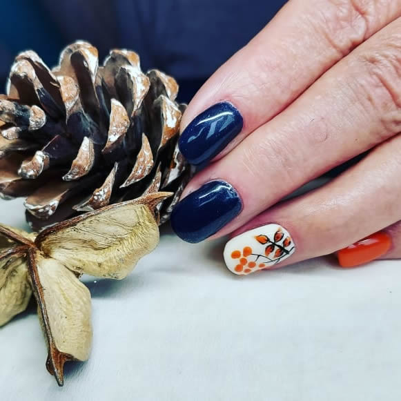 image a customers' hand with gel nails next to a pine cone and some leaves