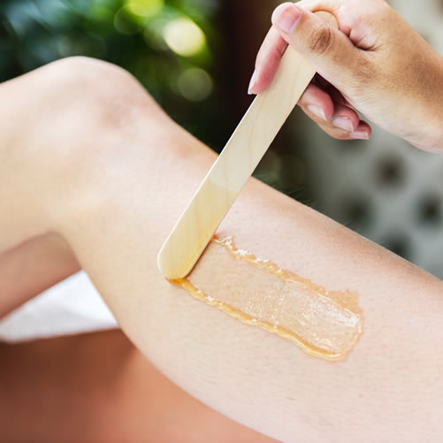image of woman's leg having wax applied