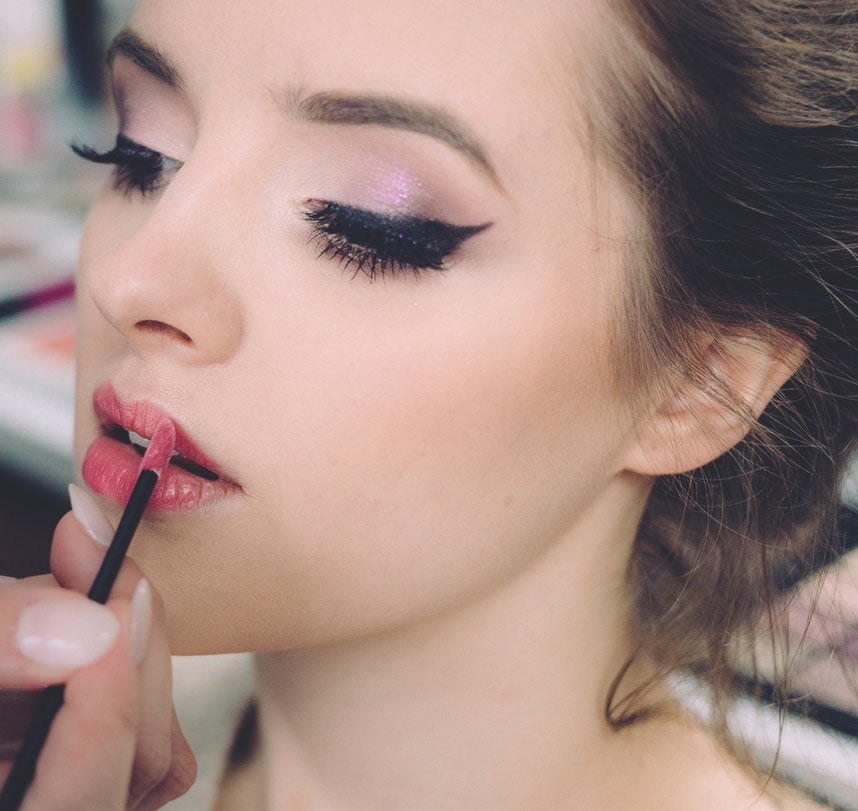 image of woman having lipstick applied with eyelashes and eyebrows done